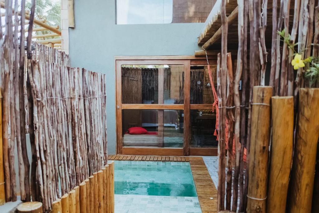 a house with a swimming pool and a wooden fence at Vila do Porto, Praia do Patacho - Bangalô Toque in Pôrto de Pedras