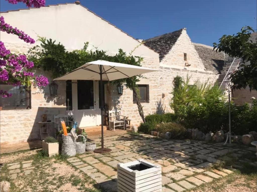 un patio con sombrilla frente a una casa en Maison Santarosa, en Castellana Grotte