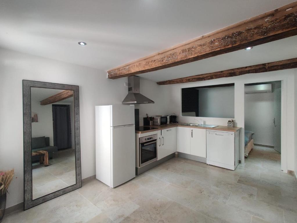 eine Küche mit weißen Geräten und einem großen Spiegel in der Unterkunft Logement neuf centre du village aux pieds du château in Grimaud