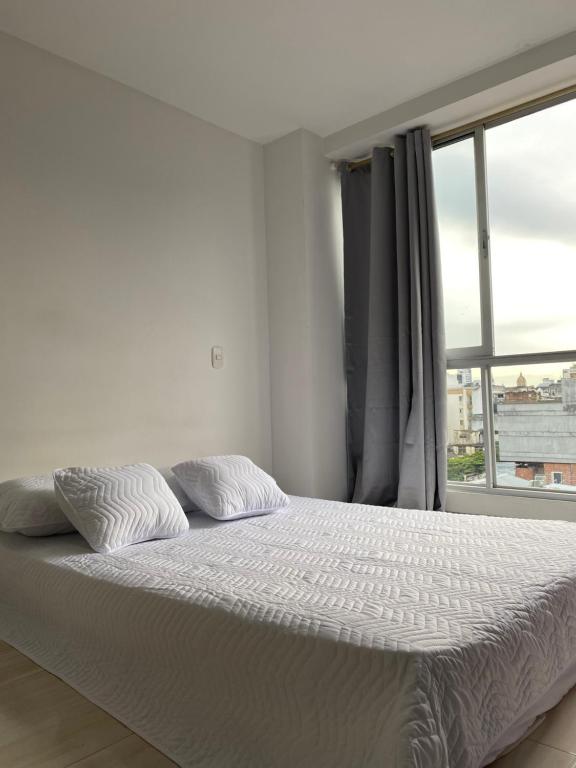 a white bed in a room with a window at Apartasuite 01 in Pereira