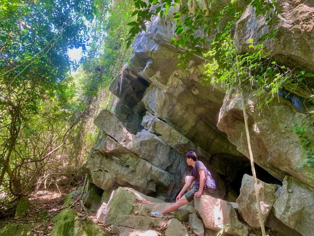 une femme assise sur un rocher dans une forêt dans l'établissement Viet Hai Lan Homestay, à Cat Ba