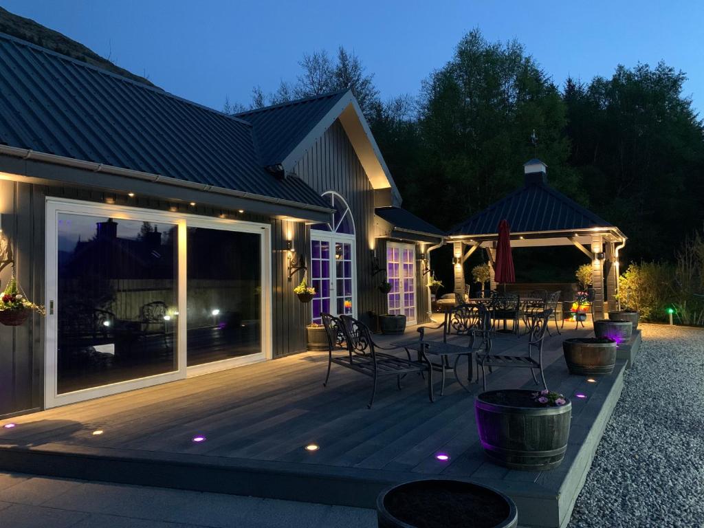 a house with a deck with a table and chairs at Little Fox Lodge Hideaway Glencoe - 5 Star with Hot Tub overlooking Loch Linnhe in Glencoe
