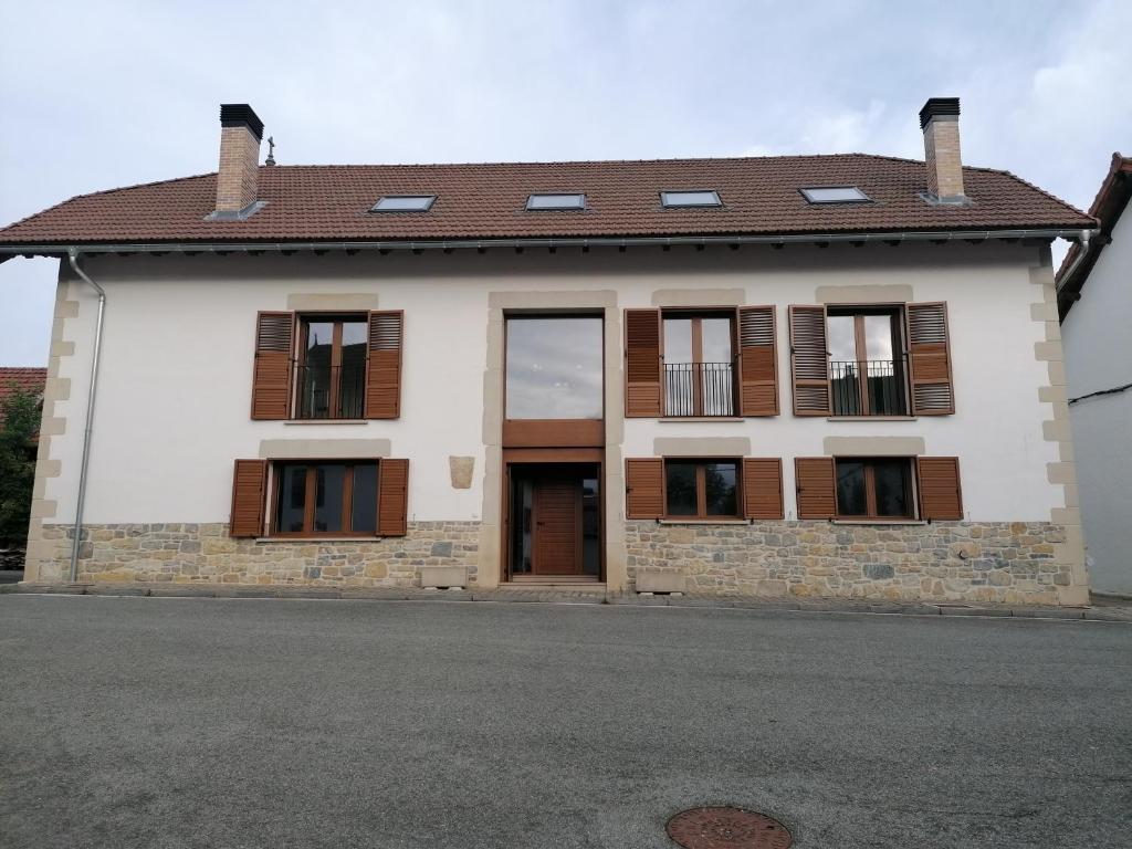 Casa blanca con ventanas marrones y calle en Casa Patxikuzuria en Espinal-Auzperri