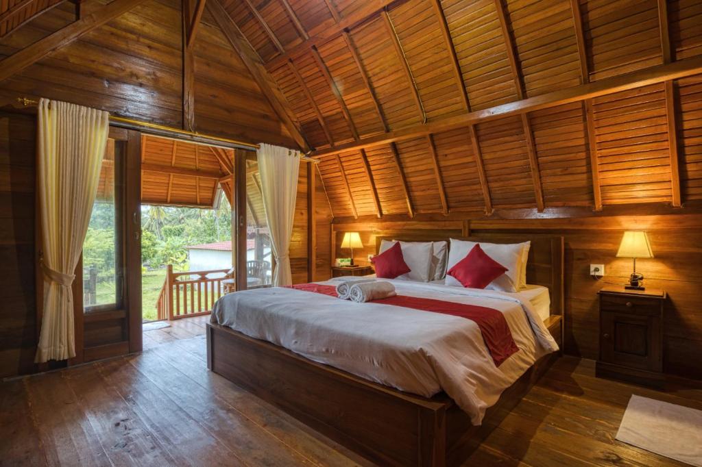 a bedroom with a large bed with a wooden ceiling at Dekara Cottages in Nusa Penida