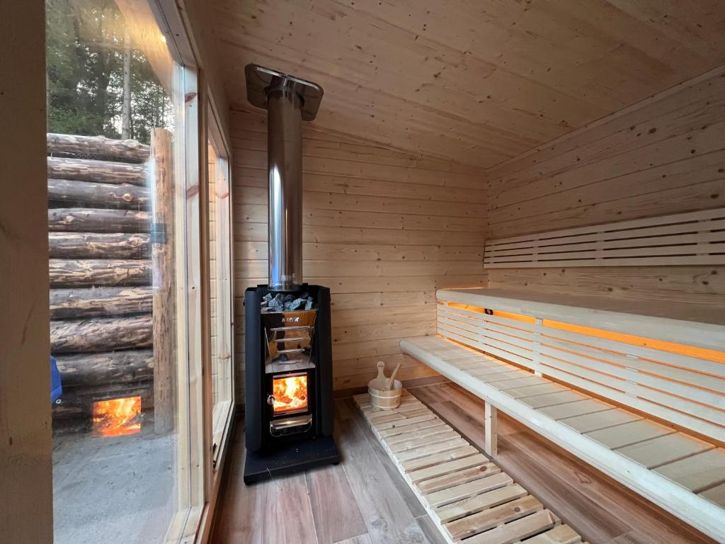 a wood stove in a sauna with a bench at EVASION gîtes et spa in Saint-Léonard