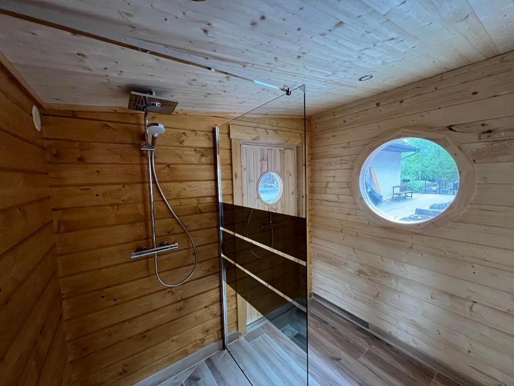 a shower in a wooden room with a window at EVASION gîtes et spa in Saint-Léonard