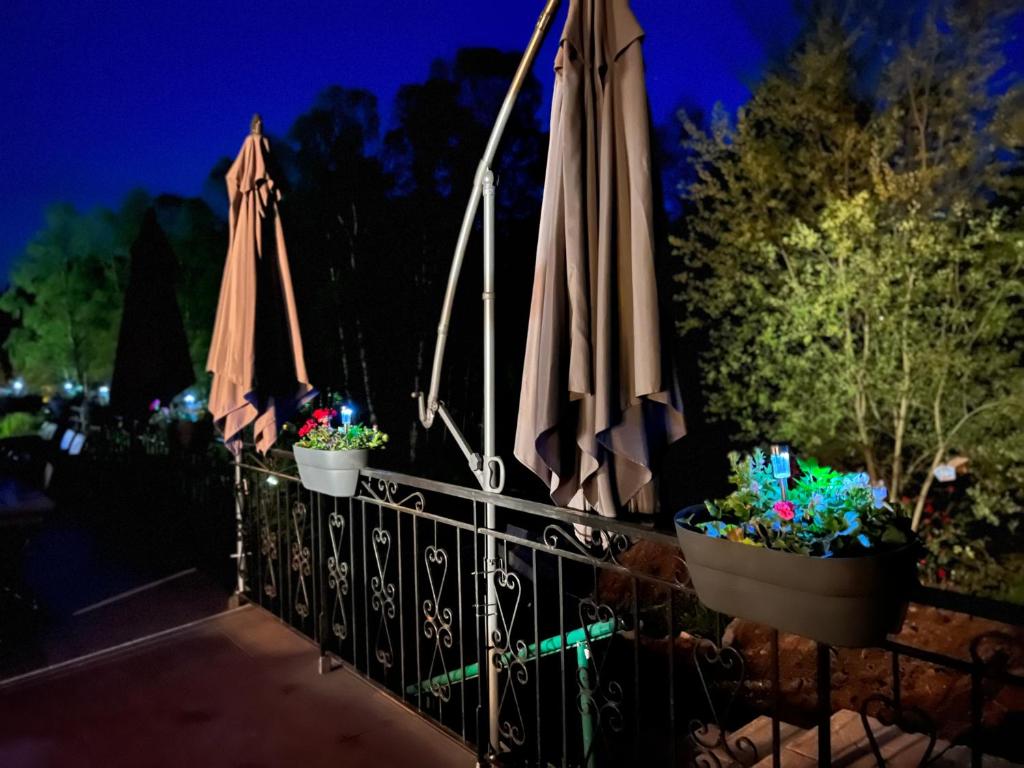 two umbrellas and flowers on a fence at night at EVASION gîtes et spa in Saint-Léonard