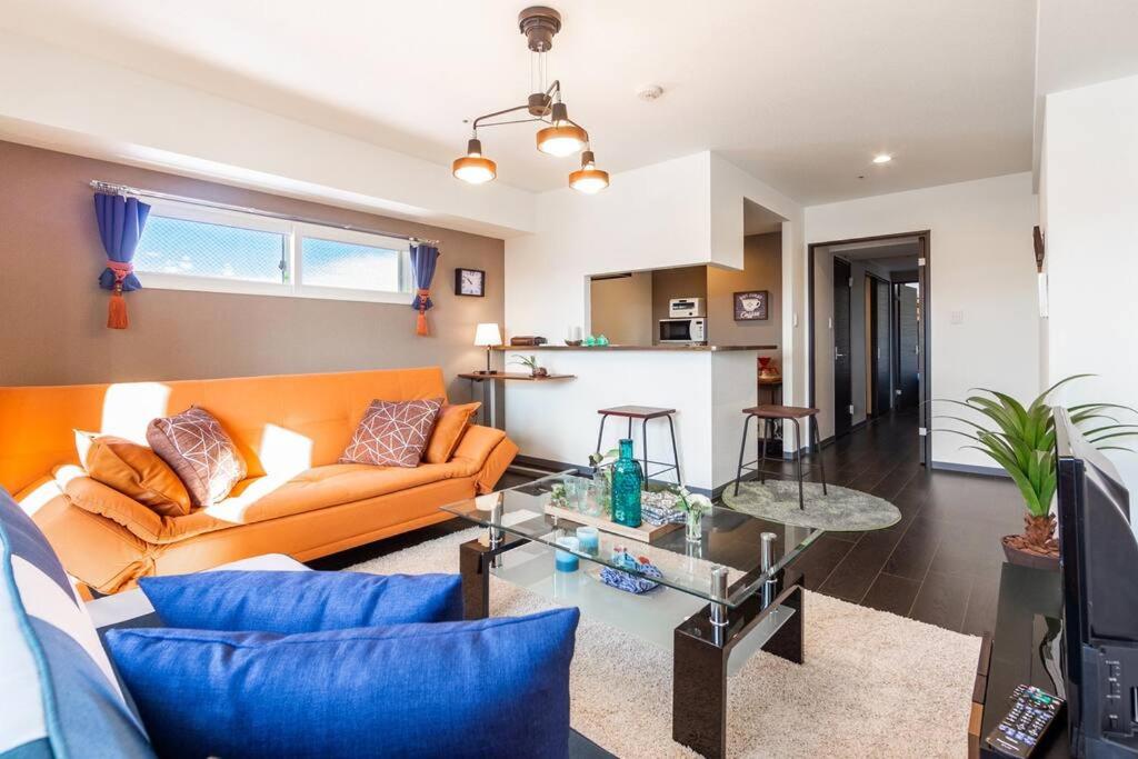 札幌的住宿－GRAVITY，客厅配有橙色沙发和玻璃桌