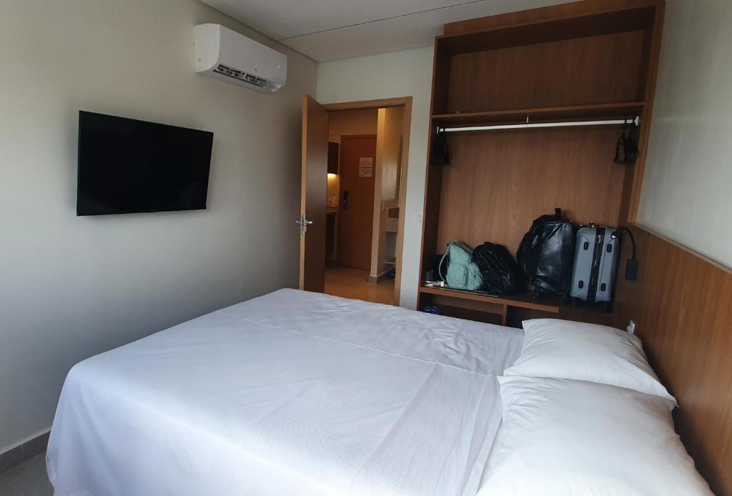 a bedroom with a white bed and a flat screen tv at SALINAS PREMIUM RESORTS in Salinópolis