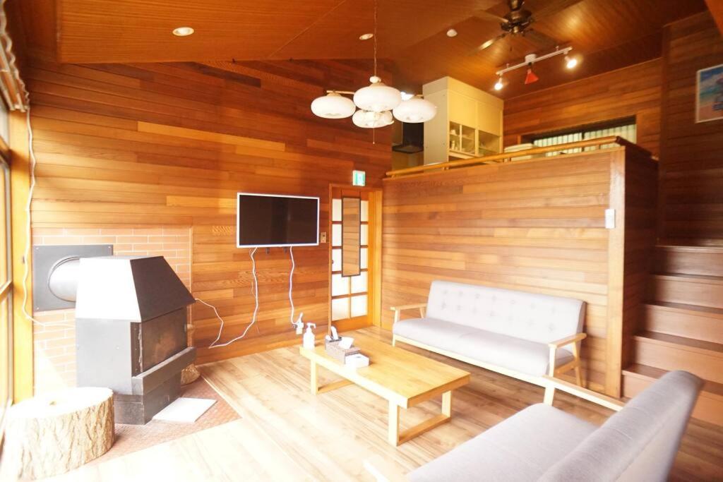 ein Wohnzimmer mit einem Sofa und einem TV in der Unterkunft 海テラス伊豆高原Ａ in Yawatano