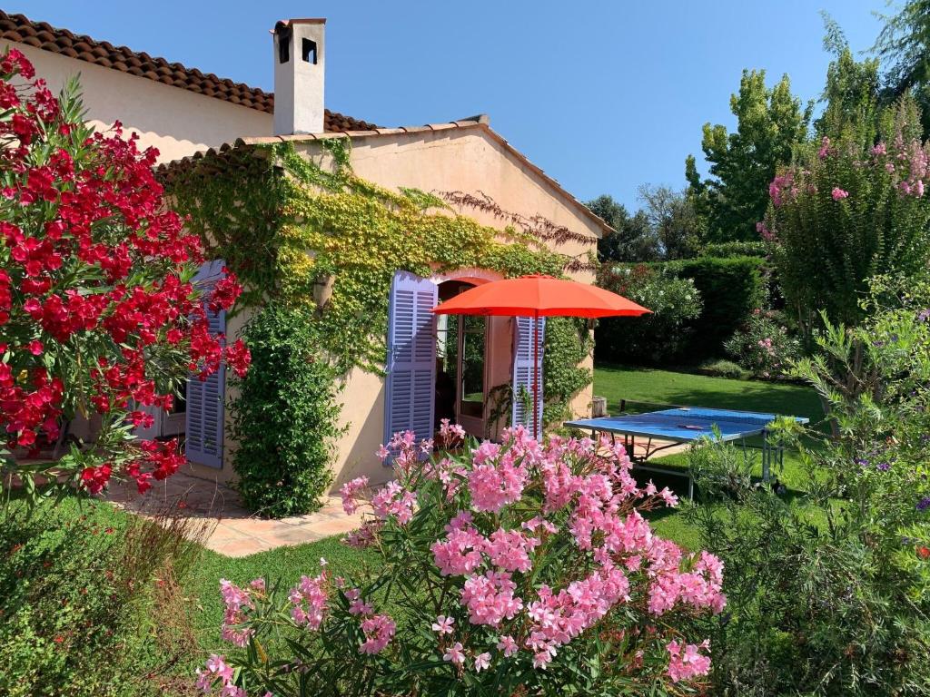 um jardim com uma mesa, um guarda-sol e flores em Beautiful villa near Valbonne with garden em Villeneuve-Loubet