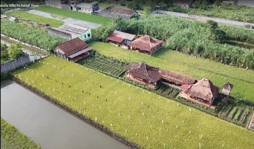 an aerial view of a farm with buildings and a river at Alamanda Family Villas, Adventure & Pool in Yogyakarta