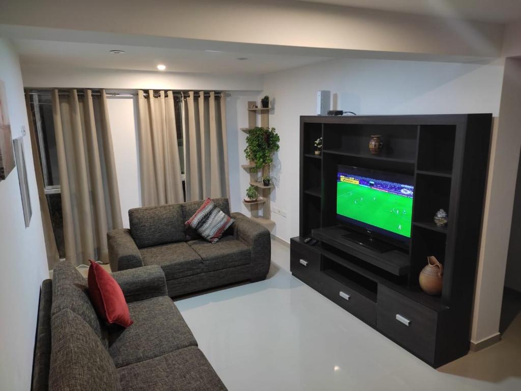ein Wohnzimmer mit einem Sofa und einem TV in der Unterkunft II - Zaguan Aparta Hotel Cusco in Cusco