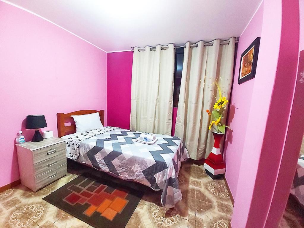 Dormitorio rosa con cama y tocador en Samay Wasi - Aeropuerto, en Lima