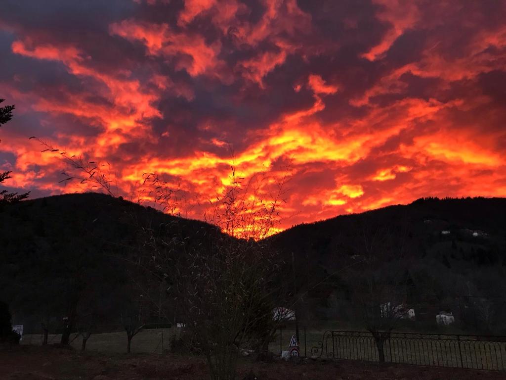 una puesta de sol ardiente con montañas en el fondo en Les Plos, gîte cosy, en Le Vigan