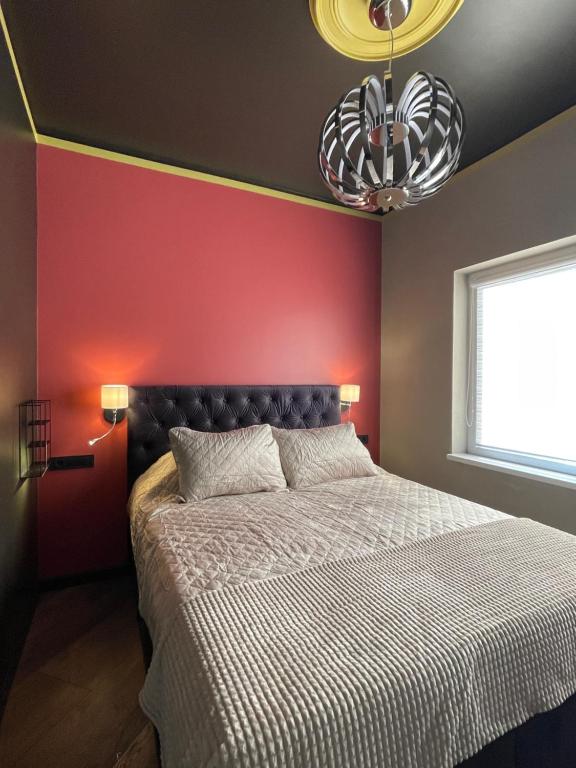 ein Schlafzimmer mit einem Bett und einer roten Wand in der Unterkunft Augšdzintari apartament in Saulkalne