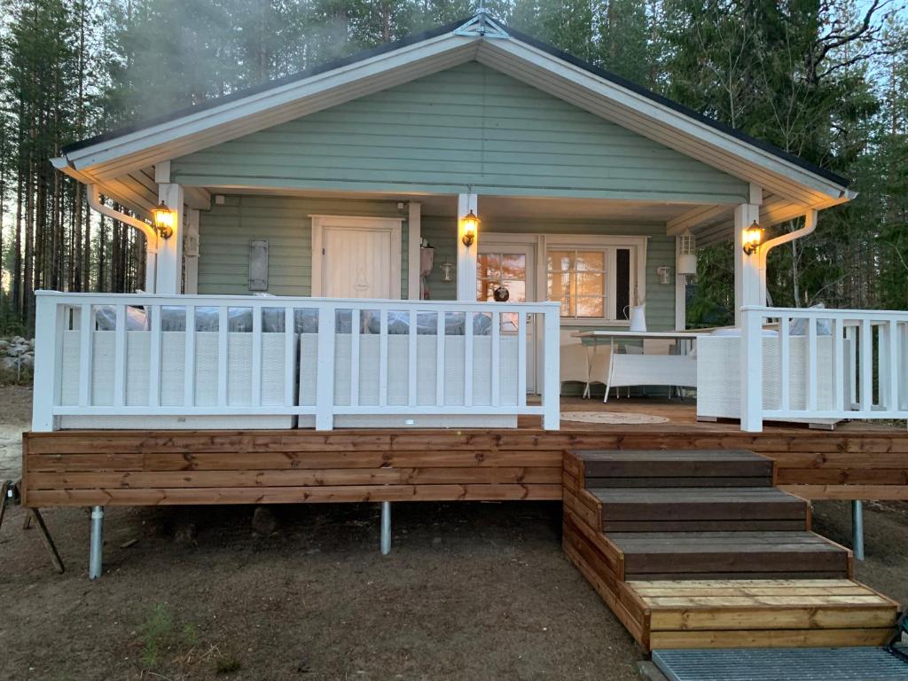 ein kleines Haus mit einer Veranda und einem weißen Geländer in der Unterkunft Loistava Aurinkoranta Mökki in Ähtäri