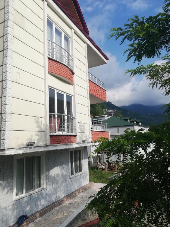 un edificio blanco con balcón y montañas de fondo en Yavuz Luxury Apartments, en Macka