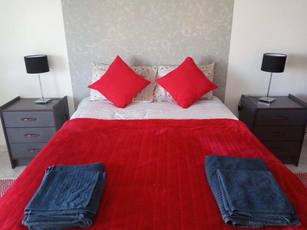 a red bed with two red pillows and two night stands at Peniche Waves in Peniche