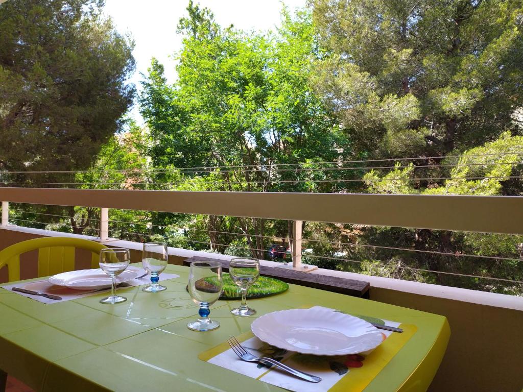 une table avec des assiettes et des verres sur un balcon dans l'établissement T2 au calme, entre mer et pinède., à Six-Fours-les-Plages