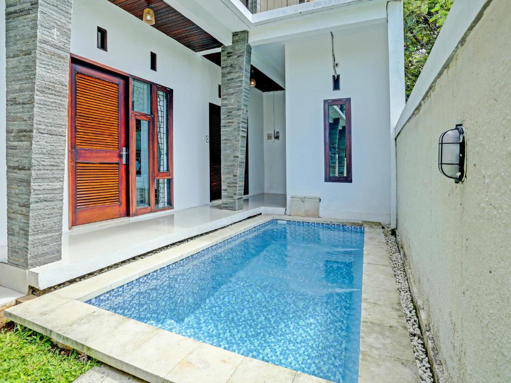 a swimming pool in the backyard of a house at OYO 91123 Madhava 108 in Ungasan