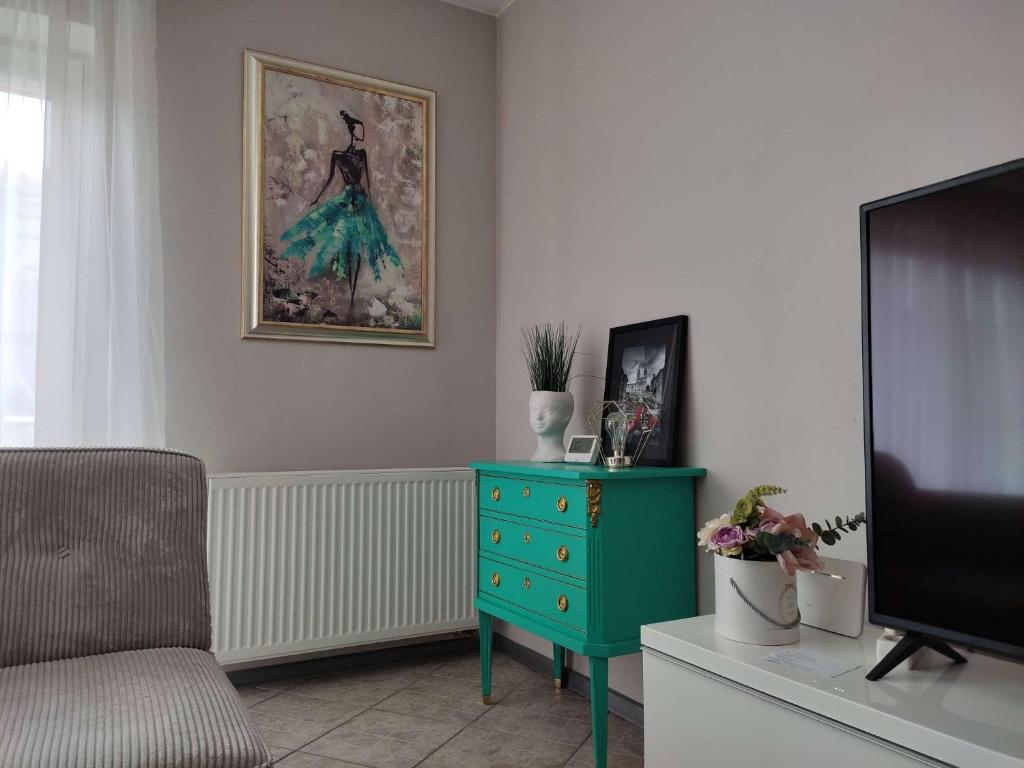 a living room with a green dresser and a tv at Apartments near old town with private parking in Kaunas