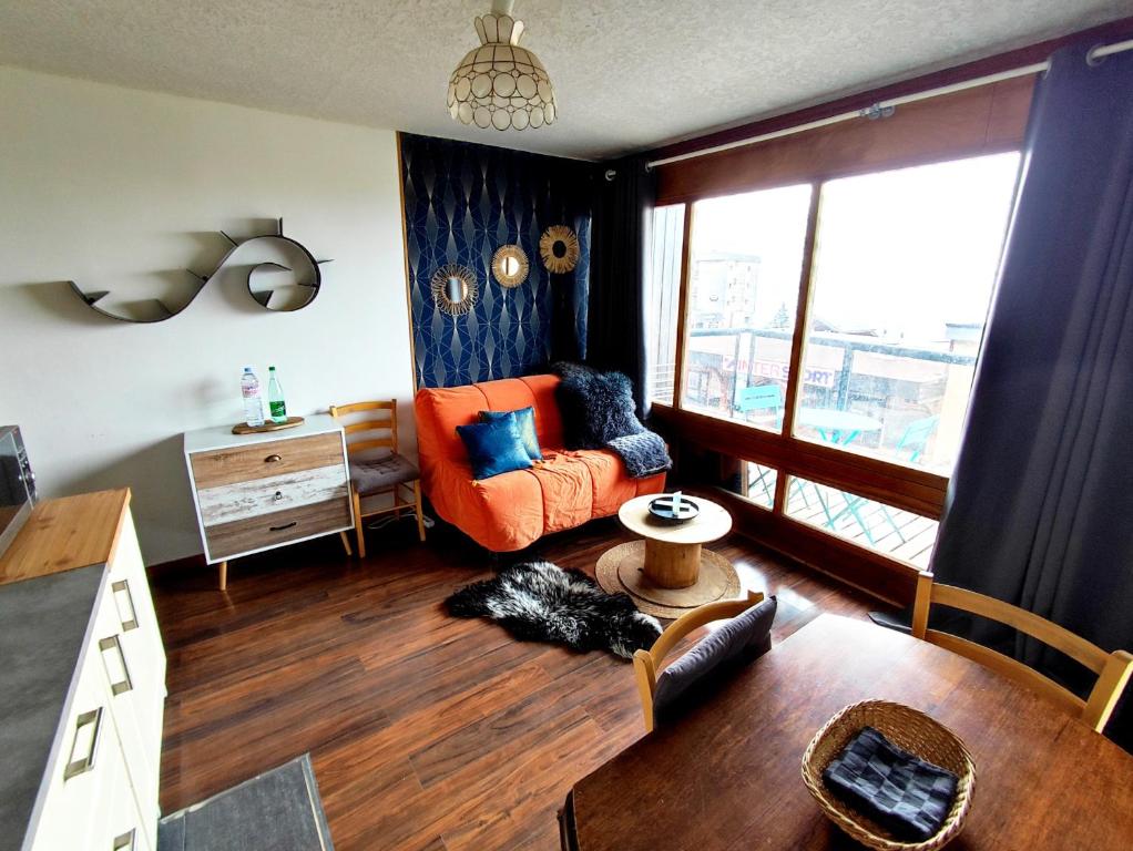 ein Wohnzimmer mit einem orangenen Sofa und einem Tisch in der Unterkunft Orcières Merlette Queyrelet 1, Front de neige in Orcières