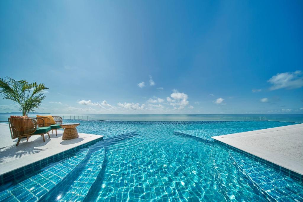 a swimming pool with a bench and the ocean at Vias Hotel Vung Tau in Vung Tau