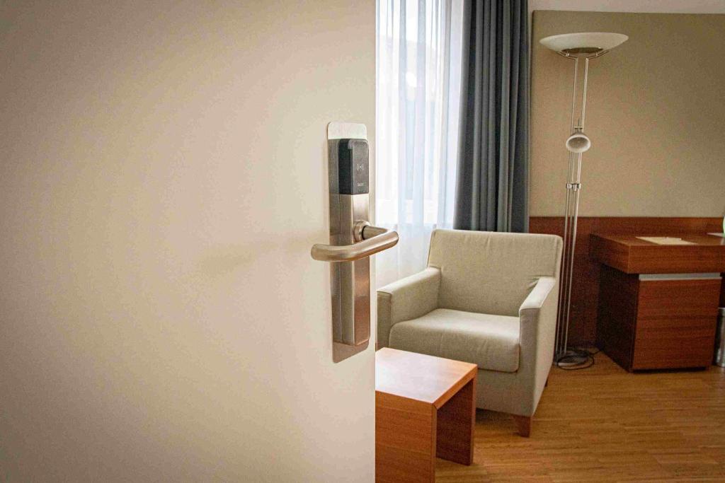 um quarto com uma cadeira e uma porta com um telefone em Gästehaus an der Oase em Versmold