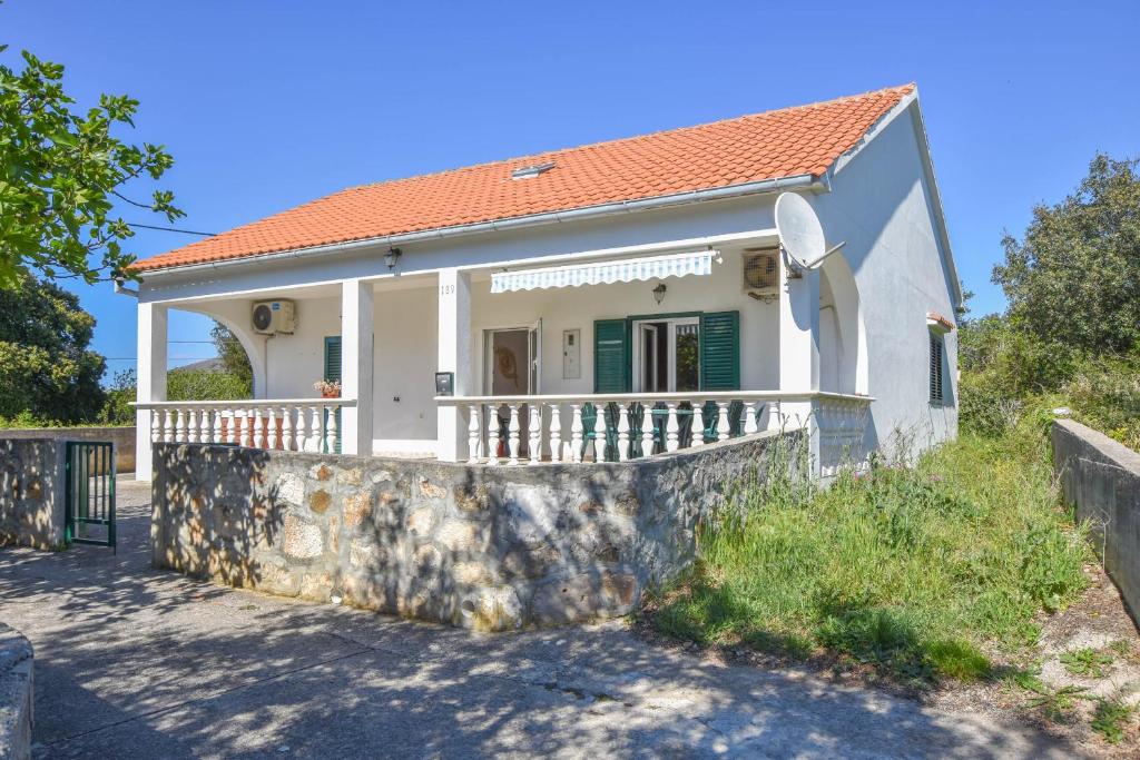 a small white house with a stone wall at House Sun and Sea in Olib