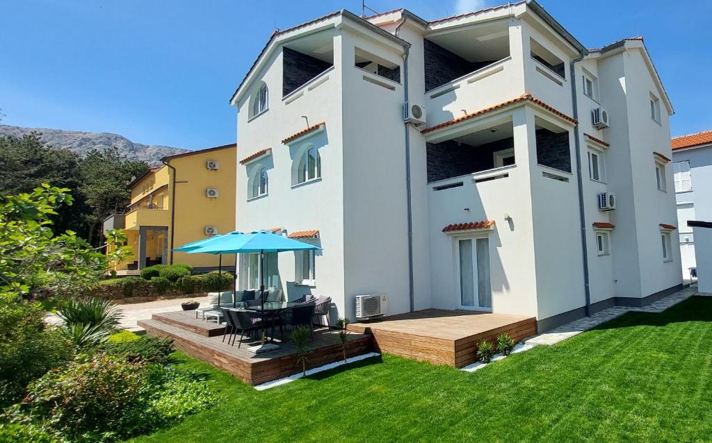 a large white house with a patio and lawn at Apartments Matea in Baška