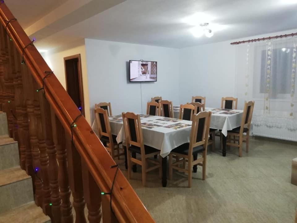 a dining room with tables and chairs and a staircase at Casa Netotea in Cîmpeni