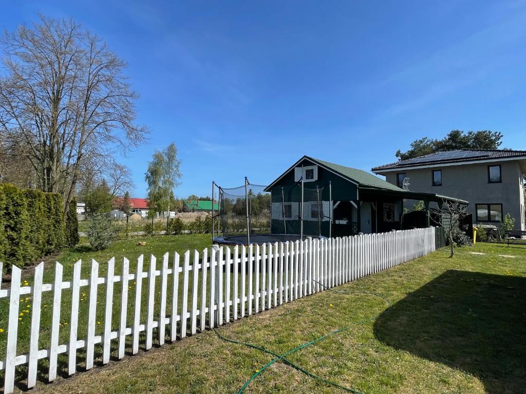 a white picket fence in front of a house at Domek letniskowy in Świnoujście