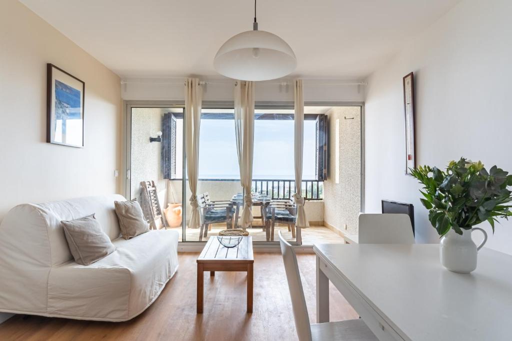 een woonkamer met een witte bank en een tafel bij TERRE MARINE - Bel appartement avec terrasse vue mer in Cassis