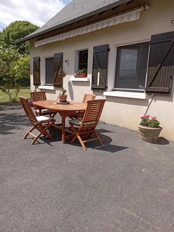 une table et des chaises en bois devant une maison dans l'établissement le gite de margot, à Beyssac