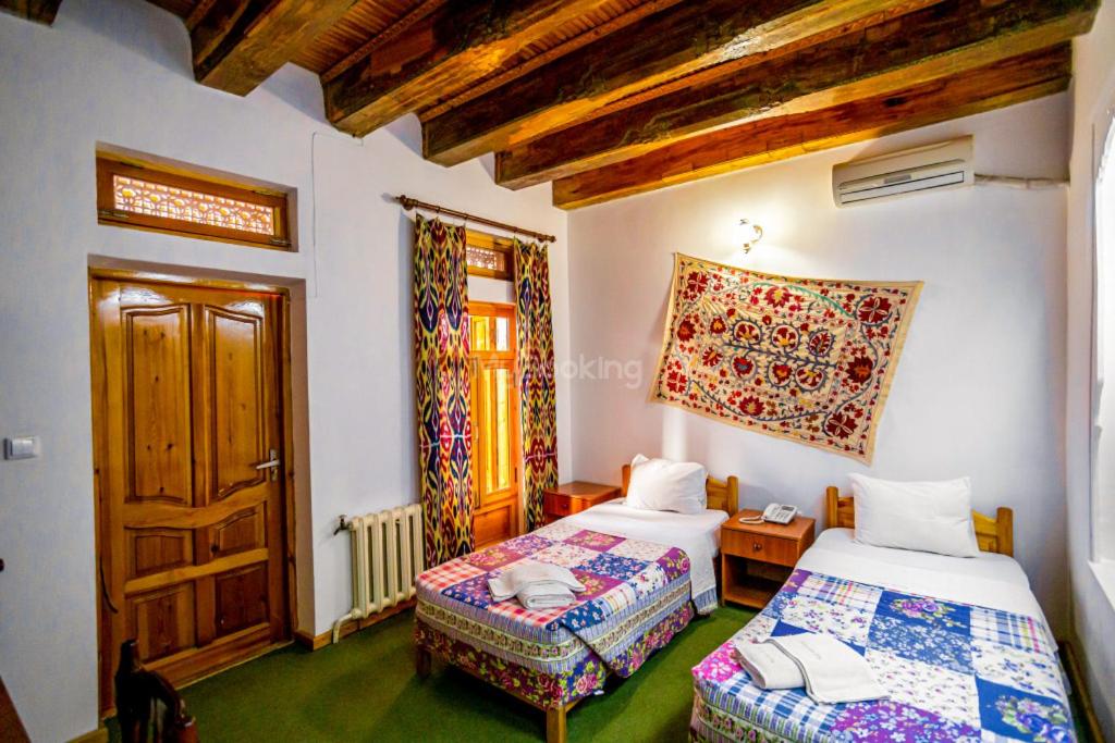 a room with two beds and a window and a door at Boutique Old City in Bukhara