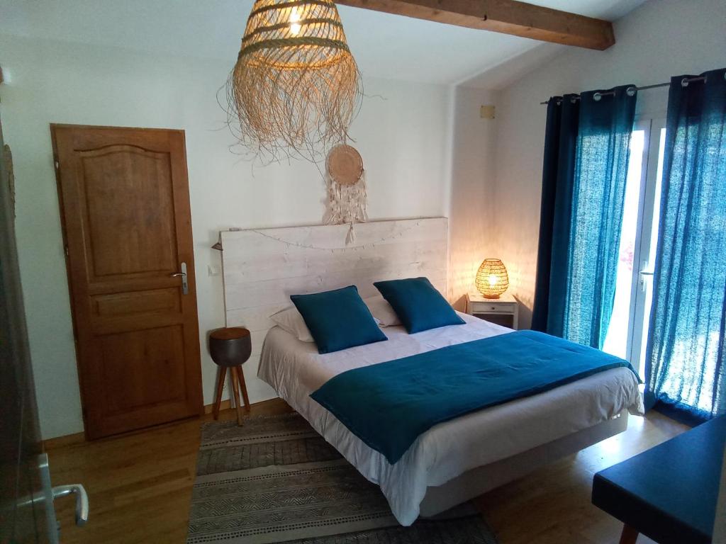 a bedroom with a bed with blue sheets and a chandelier at La Chambre Haute, spa et jardin extérieur à Nîmes in Nîmes