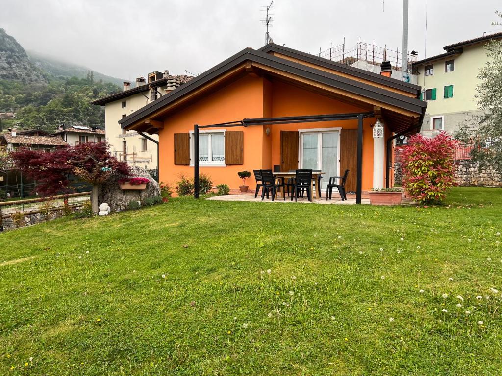 una pequeña casa naranja con una mesa en un patio en Villetta Drena, en Drena