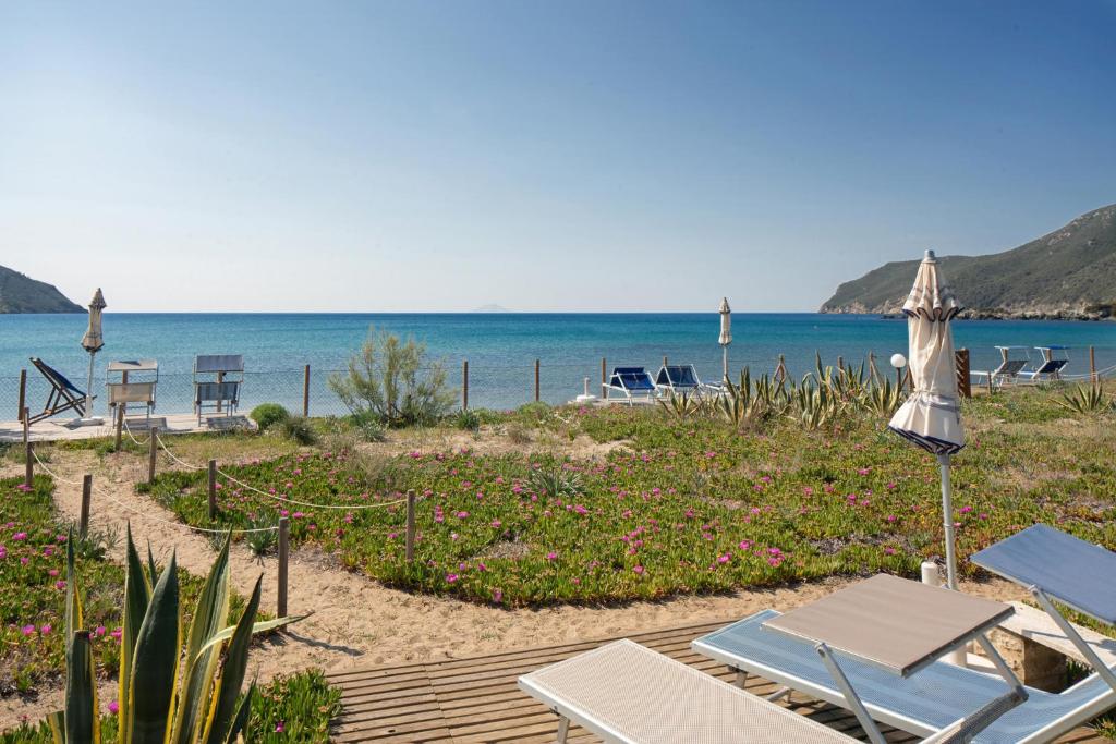 una spiaggia con sedie e ombrellone e l'oceano di Il giardino di sabbia a Lacona