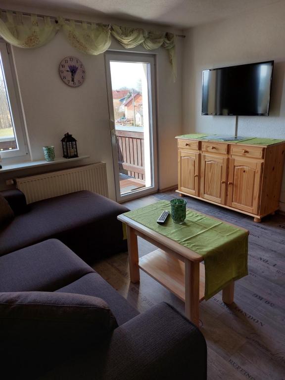 a living room with a couch and a tv and a table at Ferienwohnung Willkommen in Bad Schandau