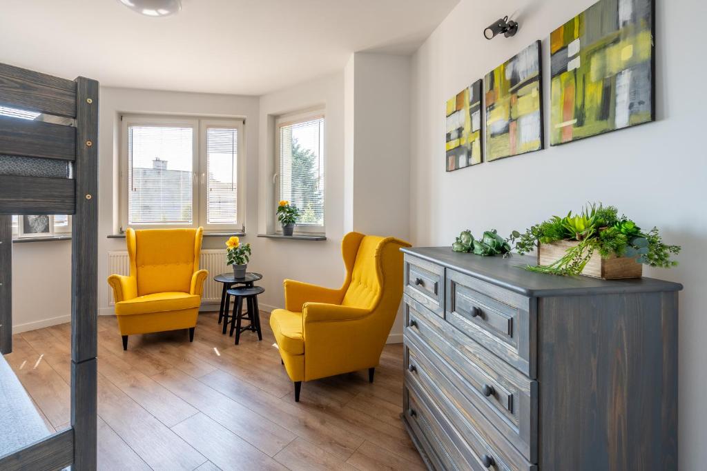 Apartament Nad Różami في أوشفيتز: غرفة نوم مع كرسيين صفراء وخزانة