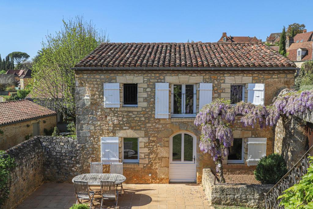 una casa in pietra con un tavolo e sedie di fronte di Charming cottage in Dordogne with swimming pool a Domme