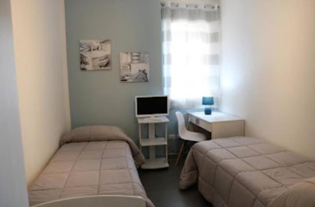 pokój z dwoma łóżkami i biurkiem z komputerem w obiekcie B&B Al Porticciolo w mieście Marsala