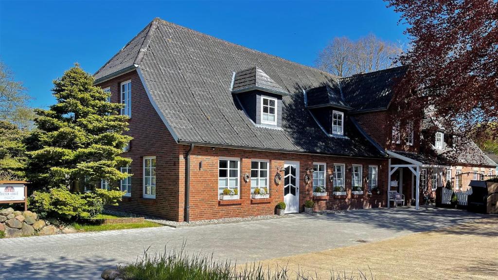 ein großes Backsteinhaus mit einem Gameradach in der Unterkunft Friesen-Lodge Ferienwohnungen in Breklum
