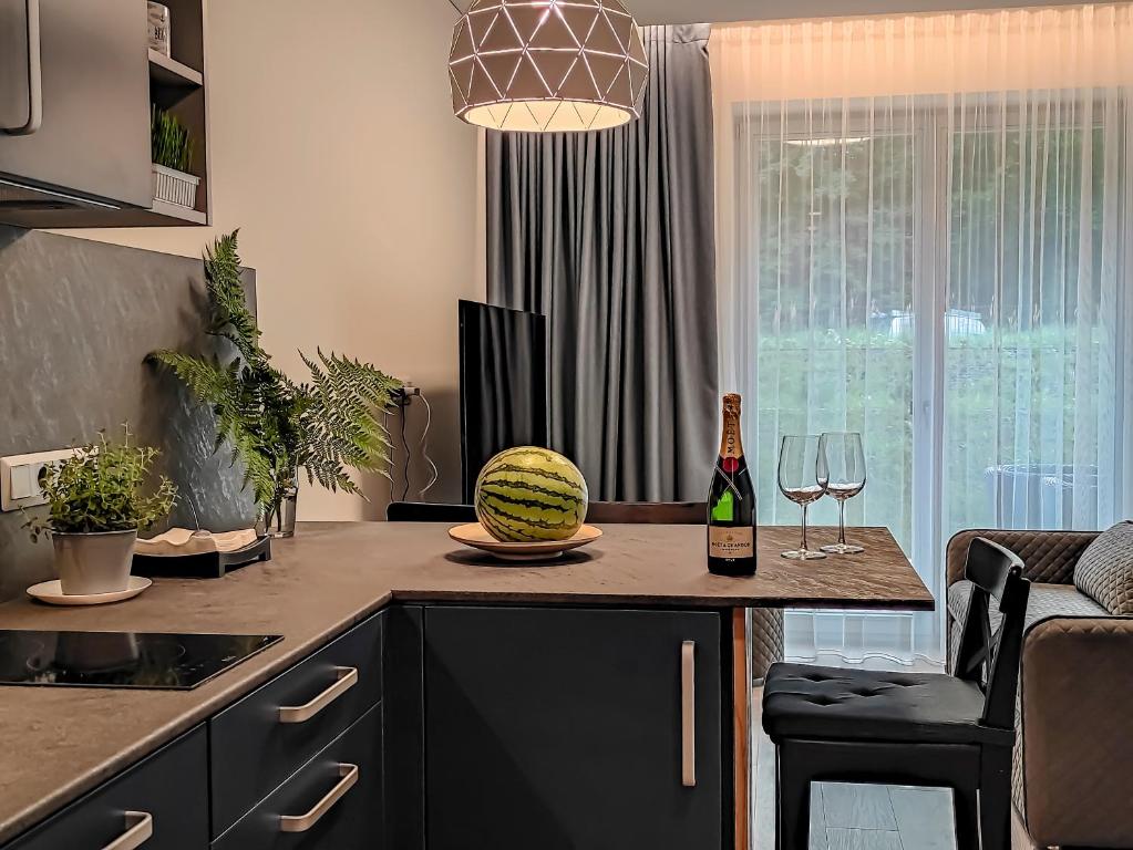 a kitchen with a bottle of wine and a watermelon on a counter at Comfy Rest apartamentai Kalno namuose in Juodkrantė