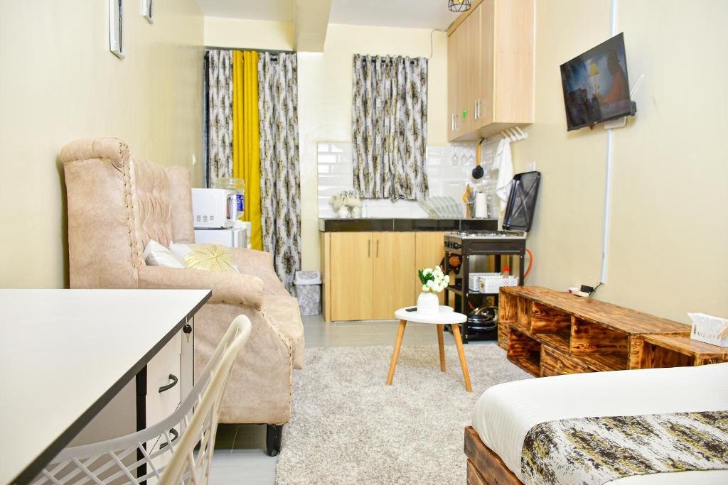 a small living room with a couch and a tv at Ruby Modern Homes Studio Apt-Imara Daima Behind Imaara Mall-JKIA-Nebula in Nairobi