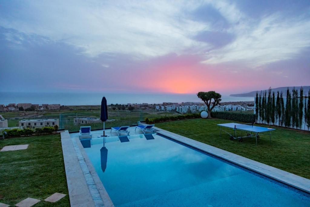 a villa with a swimming pool and a sunset at Villa Agadir Taghazout Bay Beach & Golf View in Taghazout