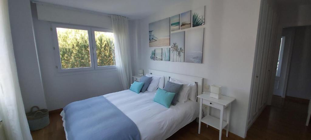 a white bedroom with a bed with blue pillows at Valdenoja-Sardinero Apartment Suite Beach in Santander