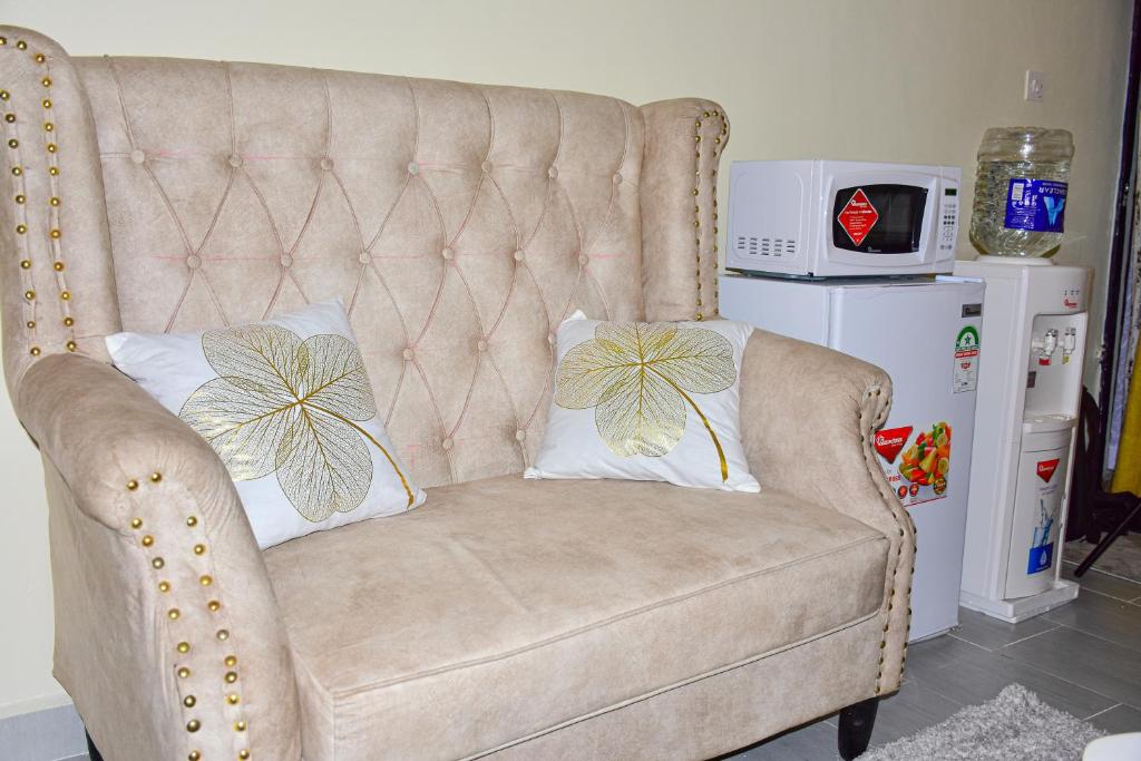 a couch with two pillows on it with a microwave at Ruby Modern Homes Studio Apt-Imara Daima Behind Imaara Mall-JKIA-Nebula in Nairobi