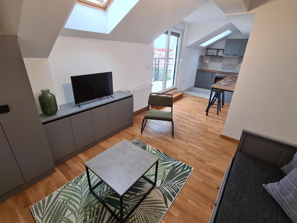 ein Wohnzimmer mit einem Flachbild-TV und einem Tisch in der Unterkunft New Now Living in Novi Sad